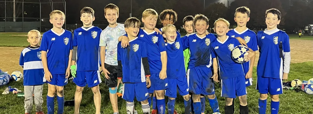 Youth Boys team posing for a picture at night under the field lights