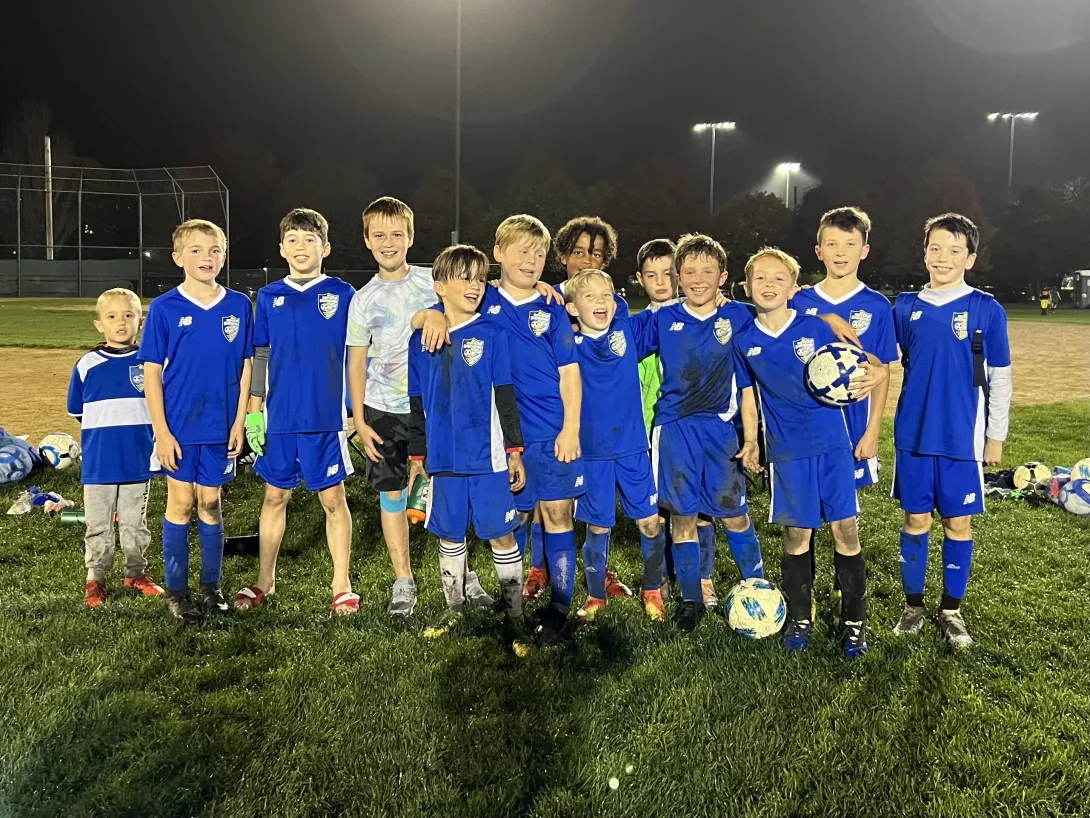 Youth Boys team posing for a picture at night under the field lights
